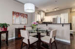 This dining area features a sleek glass-top dining table with four upholstered chairs, perfect for intimate meals.