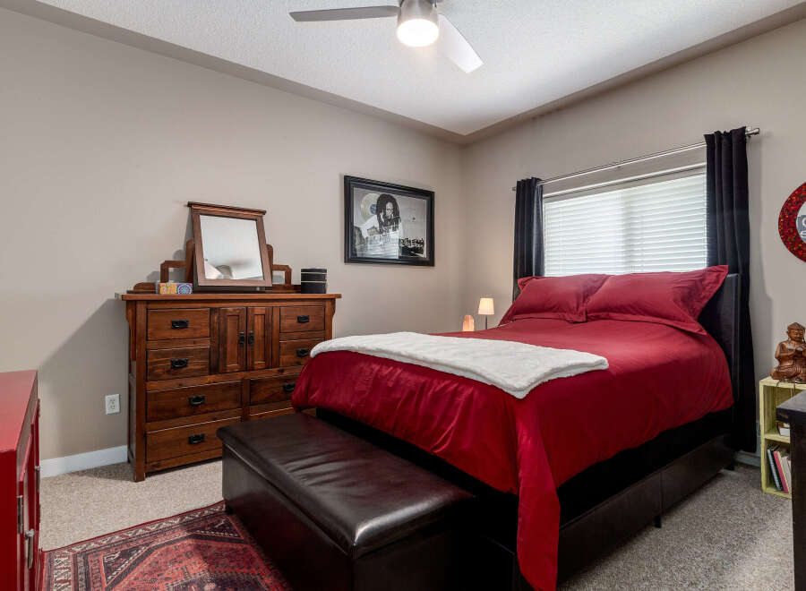 Experience comfort and style in this inviting bedroom, featuring a plush red comforter and a cozy white throw.