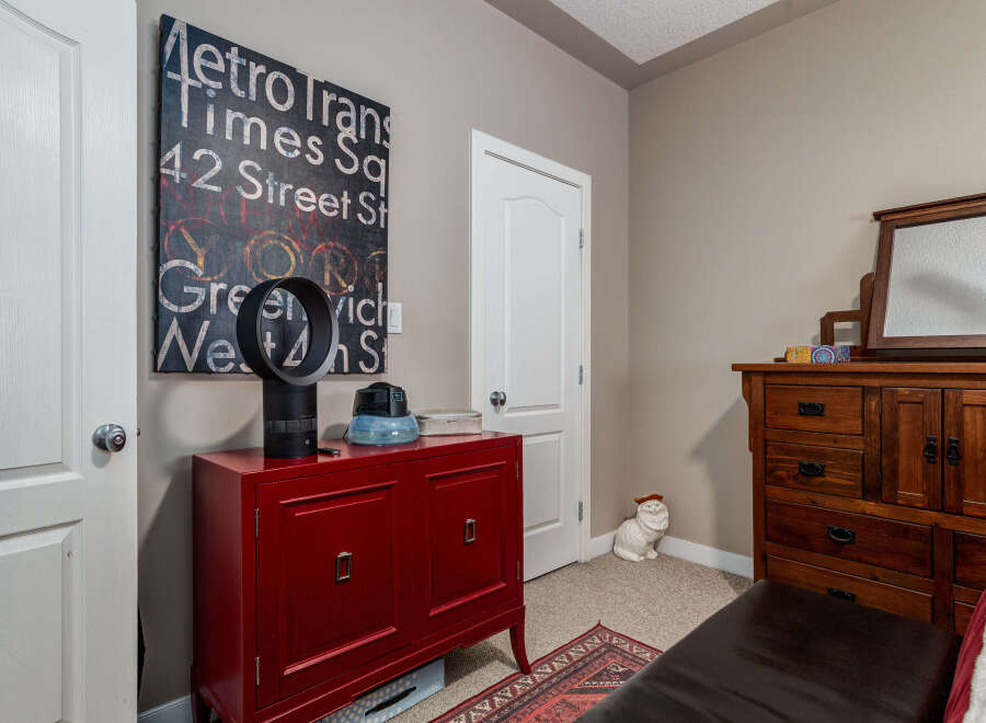 This bedroom offers a unique blend of modern and rustic elements, featuring a vibrant red cabinet and a classic wooden dresser with a mirror.