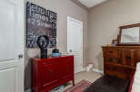 This bedroom offers a unique blend of modern and rustic elements, featuring a vibrant red cabinet and a classic wooden dresser with a mirror.
