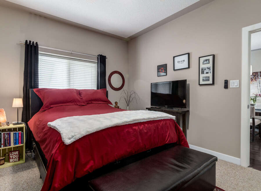 Experience ultimate comfort in this beautifully appointed bedroom, featuring a plush king-size bed with luxurious red bedding and a soft white throw.