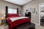 Experience ultimate comfort in this beautifully appointed bedroom, featuring a plush king-size bed with luxurious red bedding and a soft white throw.