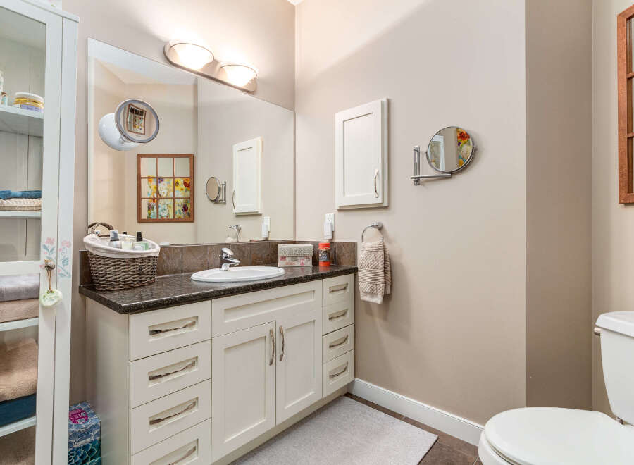 This bright and airy bathroom features a spacious vanity with ample storage and a sleek granite countertop.