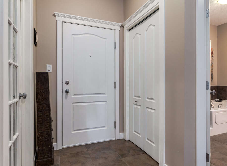 Step into this welcoming entryway featuring a classic white door with elegant trim and a matching closet door.