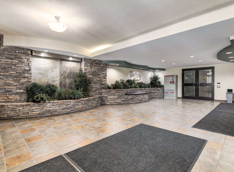 Step into a welcoming lobby featuring a stunning stone accent wall with a tranquil water feature and lush greenery.