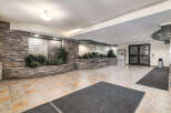 Step into a welcoming lobby featuring a stunning stone accent wall with a tranquil water feature and lush greenery.