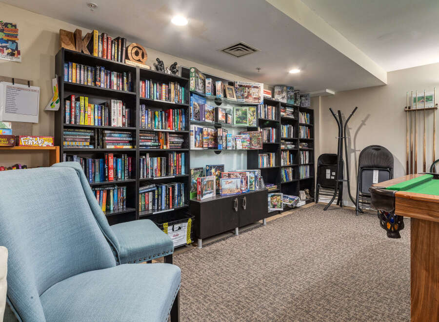 This inviting recreational space features a well-stocked lending library with a diverse collection of books and puzzles, perfect for unwinding.