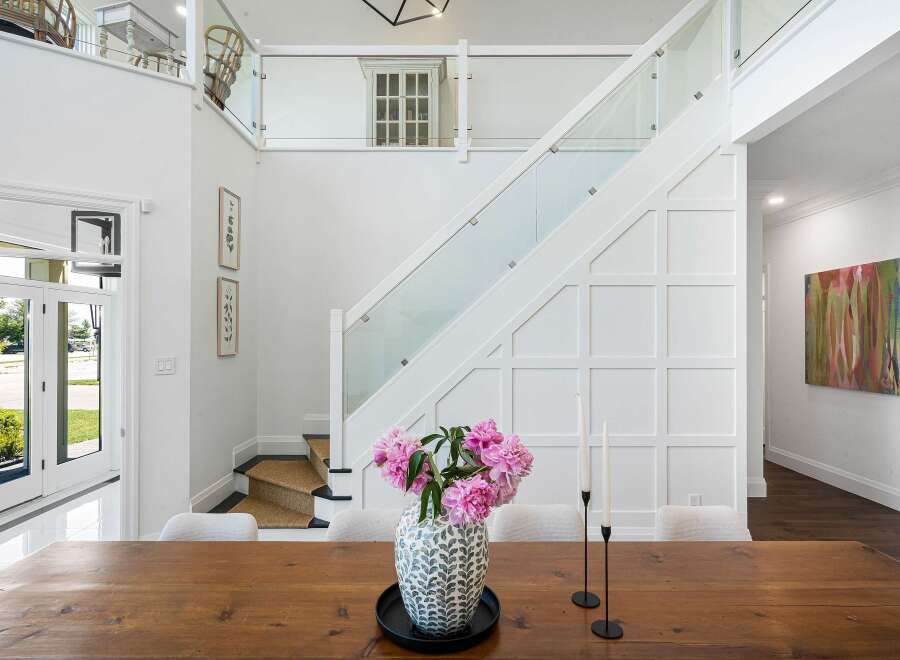 Experience modern elegance in this stunning home, featuring a grand staircase with glass railings and a striking wainscoted accent wall.