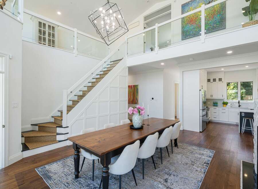 Experience modern luxury in this stunning home featuring a grand staircase with glass railings and a striking geometric chandelier.