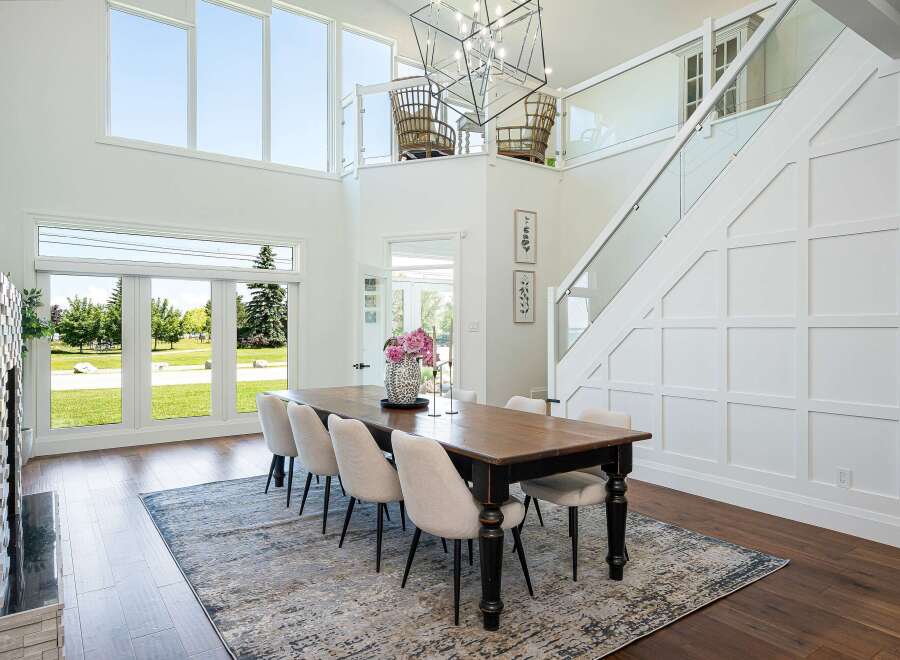 Experience luxurious modern living in this stunning dining room, featuring a grand chandelier and expansive windows that flood the space with natural light.