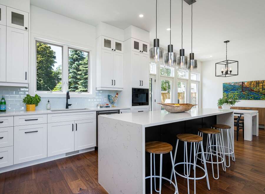 Experience modern luxury in this stunning kitchen, featuring sleek white cabinetry, a spacious quartz island with bar seating, and elegant pendant lighting.