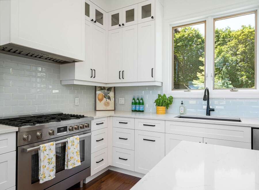 This modern kitchen boasts sleek white cabinetry and a stunning light blue subway tile backsplash.