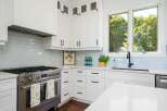 This modern kitchen boasts sleek white cabinetry and a stunning light blue subway tile backsplash.