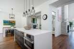 Experience modern luxury in this stunning kitchen, featuring a sleek island with a built-in oven and ample storage.