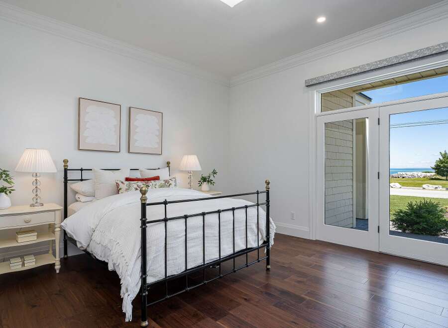 Experience coastal living in this charming bedroom featuring a classic black metal bed and elegant white nightstand.