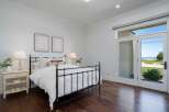 Experience coastal living in this charming bedroom featuring a classic black metal bed and elegant white nightstand.