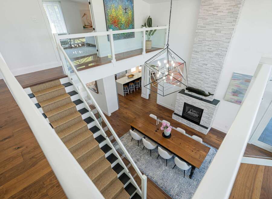 Experience modern luxury in this stunning multi-level home featuring an open-concept living area with a soaring ceiling and a striking stone fireplace.