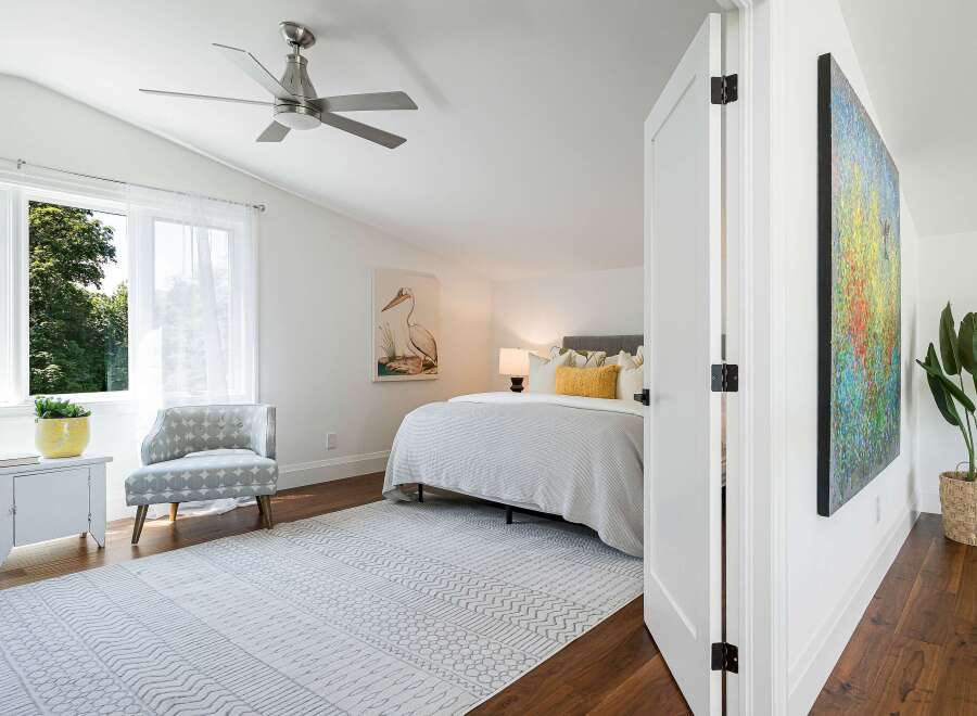 This bright and airy bedroom features a vaulted ceiling with a modern ceiling fan, perfect for year-round comfort.
