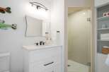 This modern bathroom features a sleek white vanity with a black faucet and a large, uniquely shaped mirror.