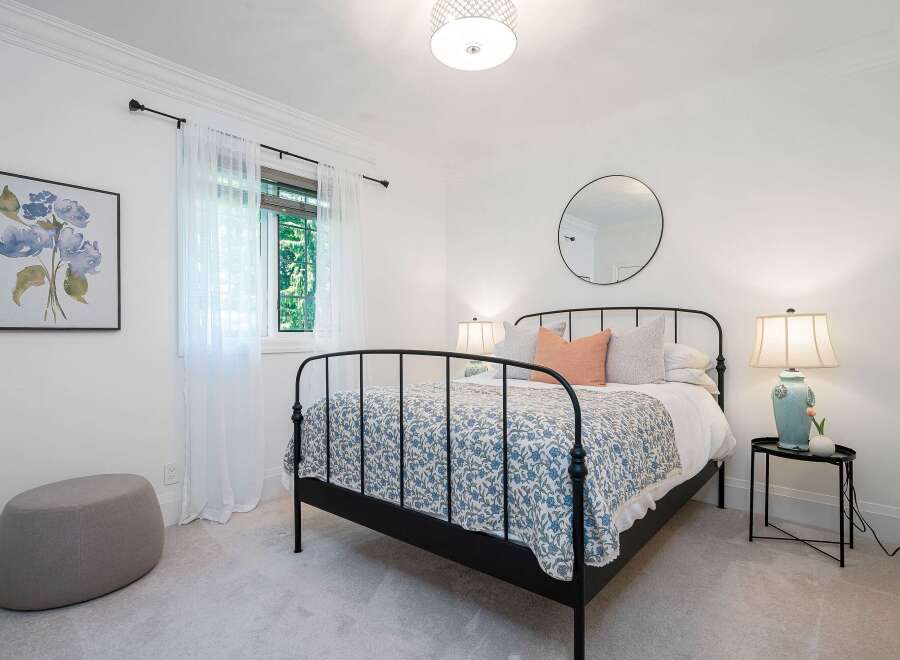 This charming bedroom features a classic black metal bed adorned with a blue floral duvet and plush pillows, creating a cozy and inviting atmosphere.