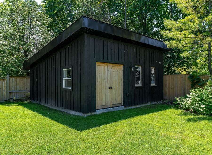 Discover this charming detached garage, perfect for storage or a workshop, nestled in a lush, green backyard.