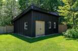 Discover this charming detached garage, perfect for storage or a workshop, nestled in a lush, green backyard.