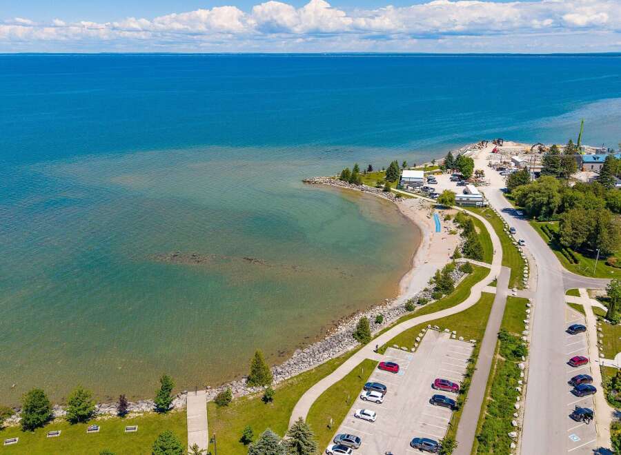 Discover waterfront living with this stunning aerial view of a serene beach and crystal-clear blue waters.