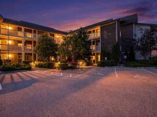 Experience comfortable living in this well-maintained apartment building, beautifully lit at dusk.