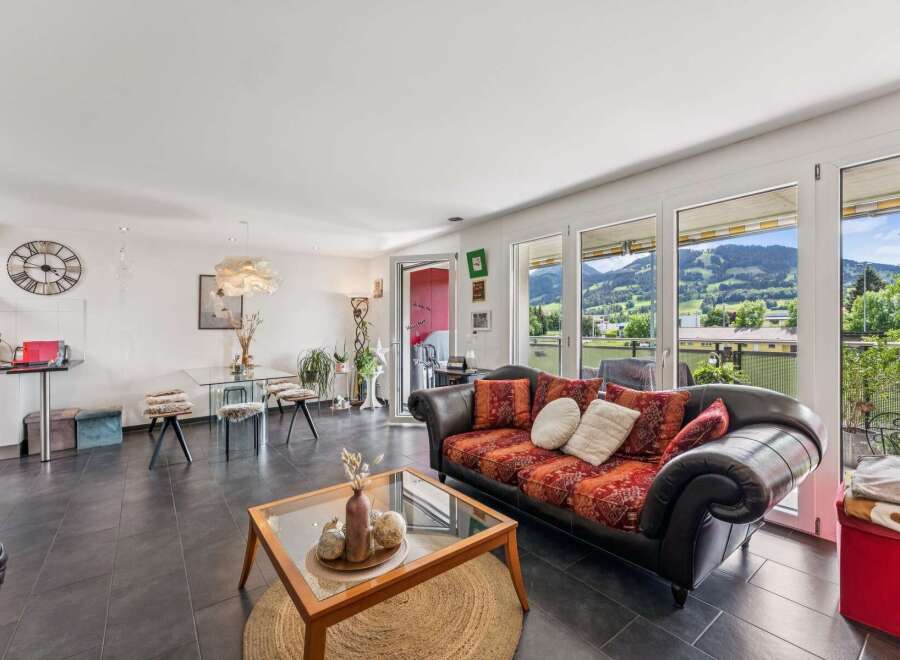 Experience breathtaking mountain views from this stunning living area, featuring a comfortable sofa with vibrant patterned cushions and a chic glass coffee table.