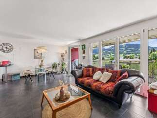 Experience breathtaking mountain views from this stunning living area, featuring a comfortable sofa with vibrant patterned cushions and a chic glass coffee table.
