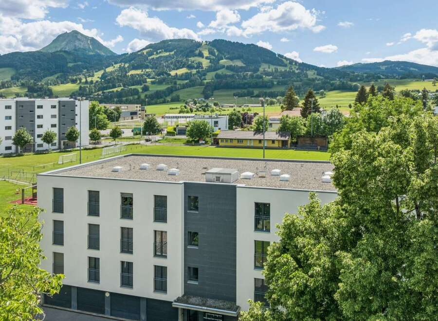 Discover modern living in this multi-story building, featuring a sleek white and gray facade with numerous balconies and large windows.