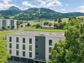 Discover modern living in this multi-story building, featuring a sleek white and gray facade with numerous balconies and large windows.
