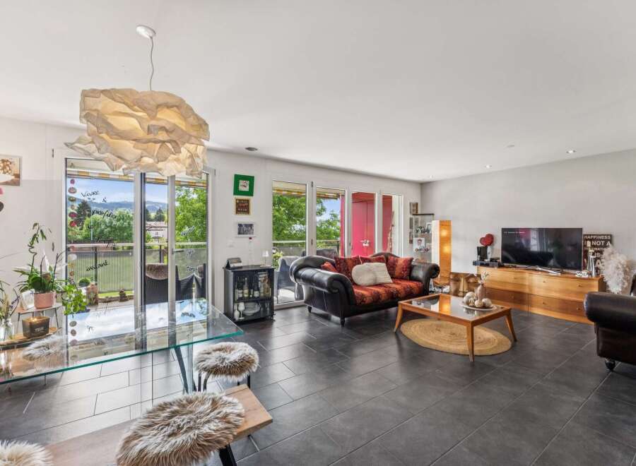 Experience modern living in this spacious open-concept living and dining area, featuring a sleek glass dining table and comfortable seating.