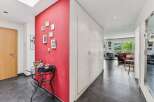 Step into this inviting hallway featuring a vibrant red accent wall adorned with a collection of framed pictures, creating a warm and personal touch.