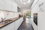 This modern kitchen features sleek white cabinetry and a dark granite countertop, complemented by a stainless steel sink and faucet.