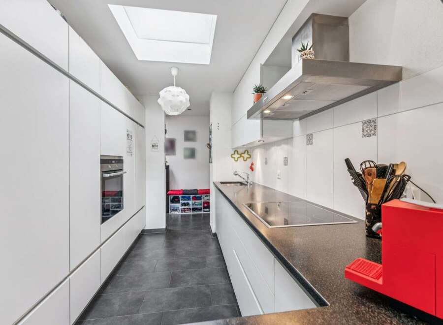 This modern kitchen features sleek white cabinetry and a spacious dark granite countertop, perfect for meal preparation.