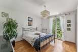This charming bedroom features a comfortable bed with a decorative duvet and a metal frame, complemented by a large potted plant and tasteful wall art.