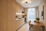 Discover this modern kitchen and dining area, featuring sleek, light wood cabinetry and integrated appliances.