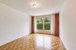 This empty room features a beautiful parquet floor that reflects the natural light streaming in from the large double doors.