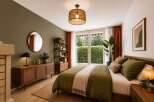 Discover this serene bedroom featuring a cozy queen-size bed dressed in olive green linens, complemented by a natural woven rug and a rattan accent dresser.