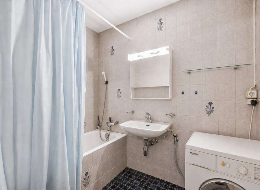 This compact bathroom features a practical layout with a bathtub and shower combination, ideal for maximizing space.