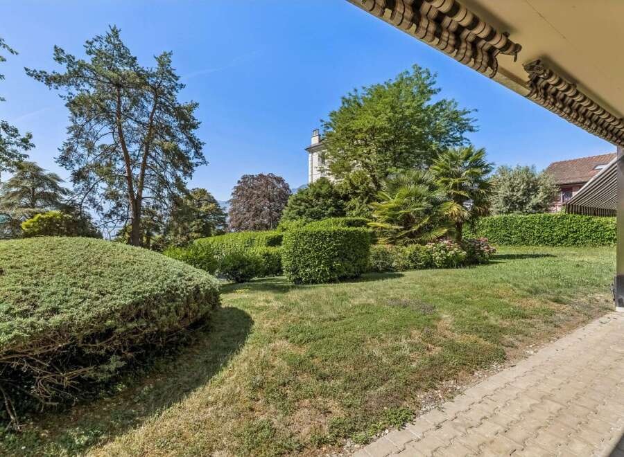 Discover this beautifully landscaped garden, featuring lush green lawns, manicured hedges, and mature trees providing ample shade.
