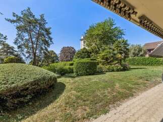 Discover this beautifully landscaped garden, featuring lush green lawns, manicured hedges, and mature trees providing ample shade.