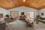 Experience the warmth of this inviting living space, featuring a stunning vaulted wood-paneled ceiling and a cozy fireplace.