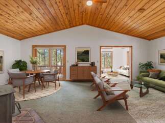 Experience the warmth of this inviting living space, featuring a stunning vaulted wood-paneled ceiling and a cozy fireplace.
