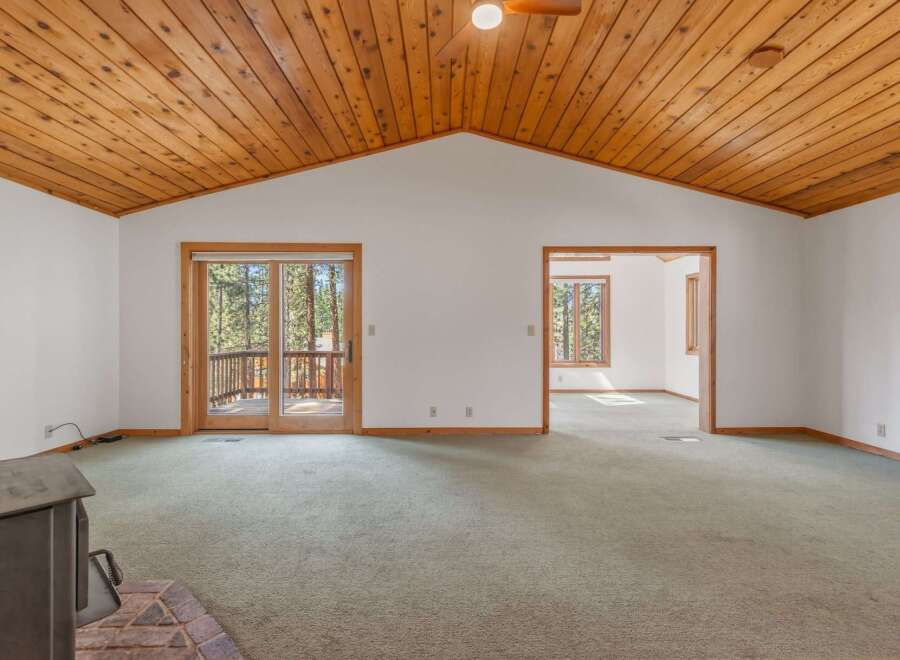 Step into this spacious living area featuring a vaulted wood-paneled ceiling and a cozy brick fireplace.
