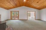 Step into this spacious living area featuring a vaulted wood-paneled ceiling and a cozy brick fireplace.