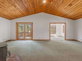 Step into this spacious living area featuring a vaulted wood-paneled ceiling and a cozy brick fireplace.