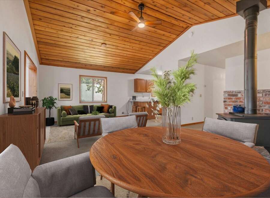 Experience cozy living in this charming home featuring a vaulted wood-paneled ceiling and a rustic brick fireplace with a wood-burning stove.