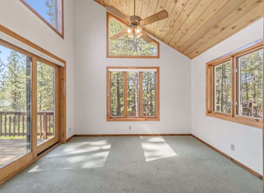 Experience breathtaking natural beauty from this stunning room, featuring expansive windows and a sliding glass door that open to a serene forest view.